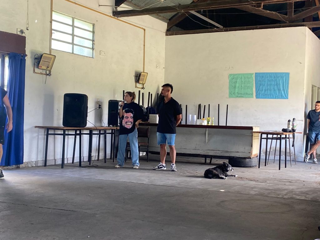 Dos militantes hablan por micrófono durante el lanzamiento, en el salón.