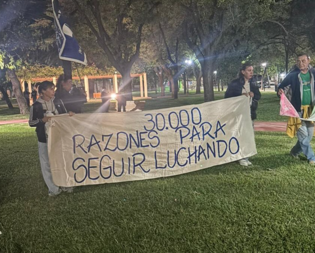 Militantes sostienen una bandera con la consigna «30.000 razones para seguir luchando».