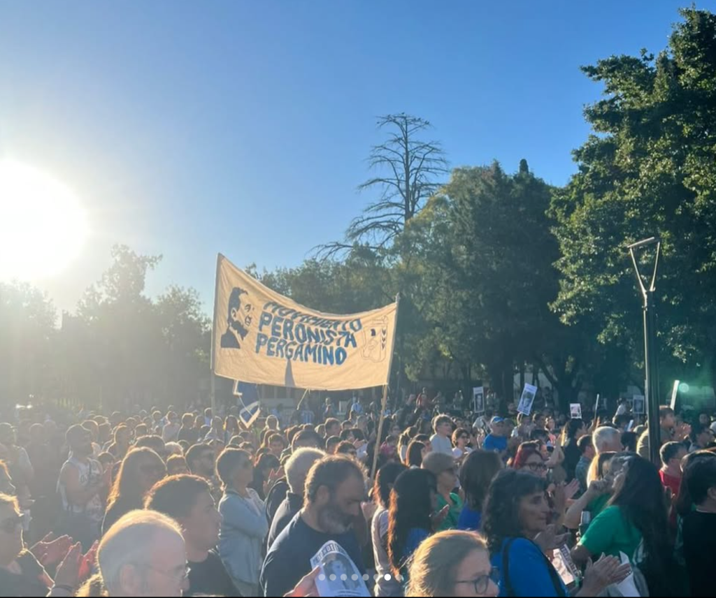 La bandera del espacio sobre la multitud, a contraluz del atardecer.