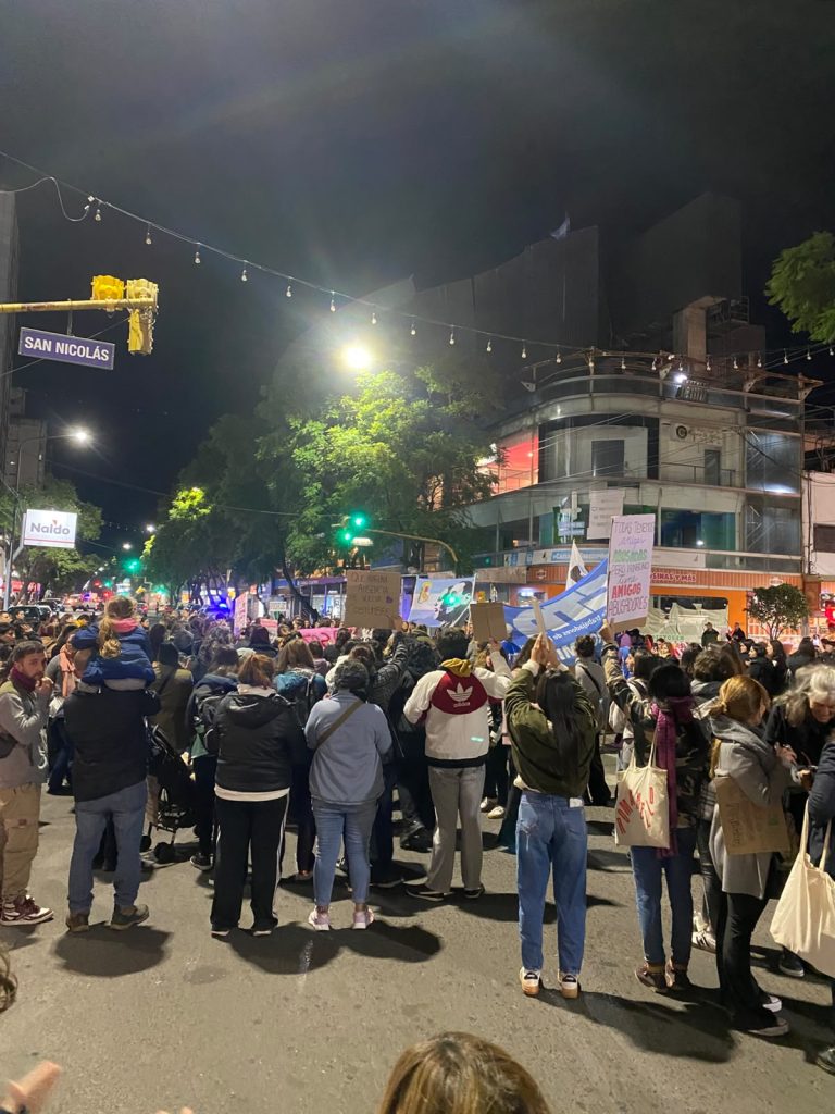 La marcha avanza por el centro al caer la noche, con carteles y banderas.
