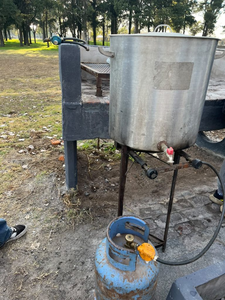 La olla sobre el fuego, con la garrafa al costado, en el parque.