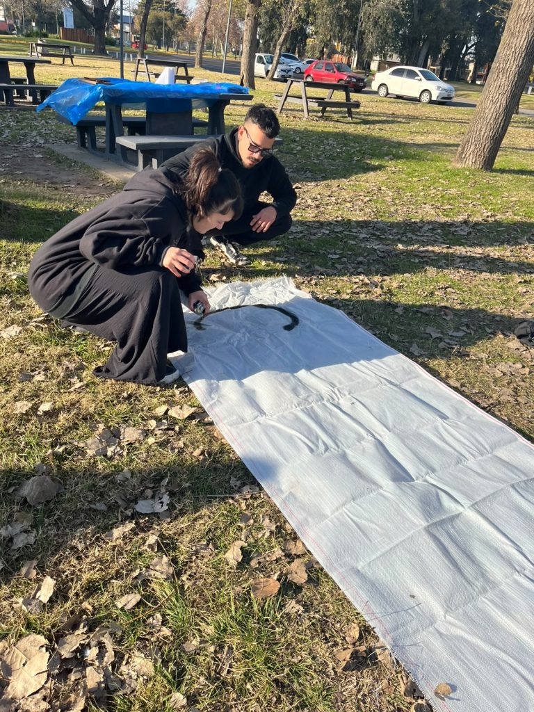Dos militantes preparan el puesto sobre una lona, en el parque.