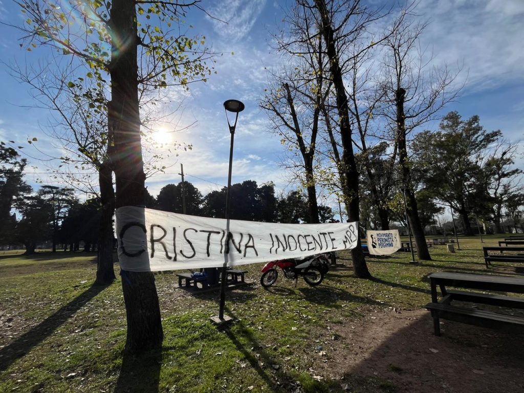 Bandera pintada a mano con la consigna «Cristina inocente», colgada entre los árboles.