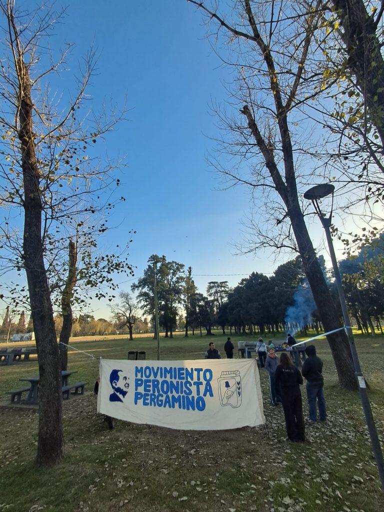 La bandera del Movimiento Peronista Pergamino colgada entre los árboles, junto al puesto.