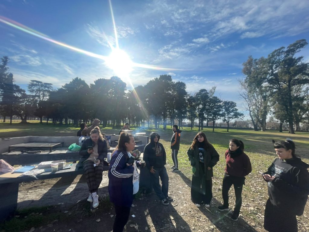 Militantes conversan junto a las mesas del parque, a contraluz del sol.