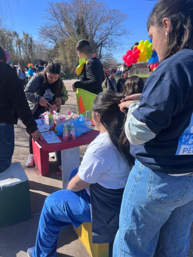 Militantes reparten la merienda en una mesa con globos, rodeados de chicos.