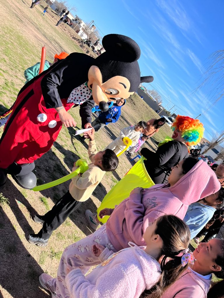 Chicos en la mesa de manualidades junto al personaje disfrazado y una payasa.