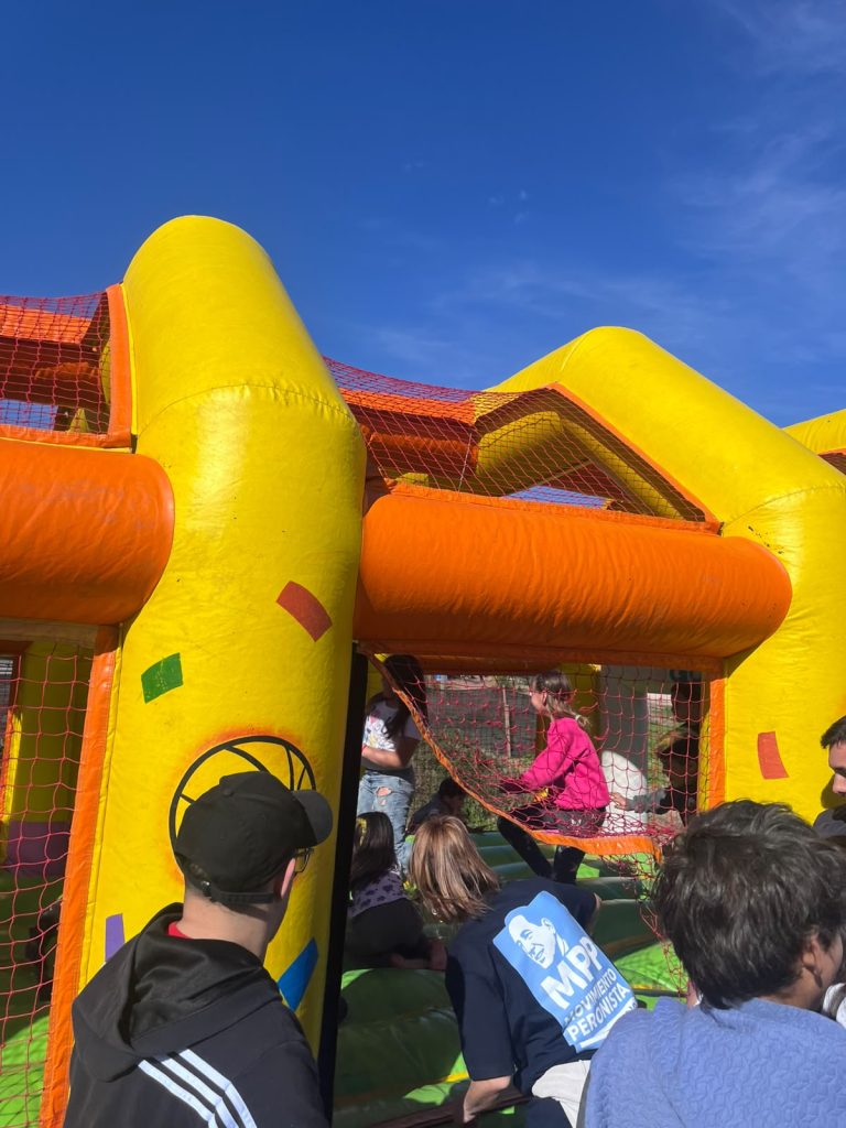 Chicos haciendo cola frente al castillo inflable amarillo.