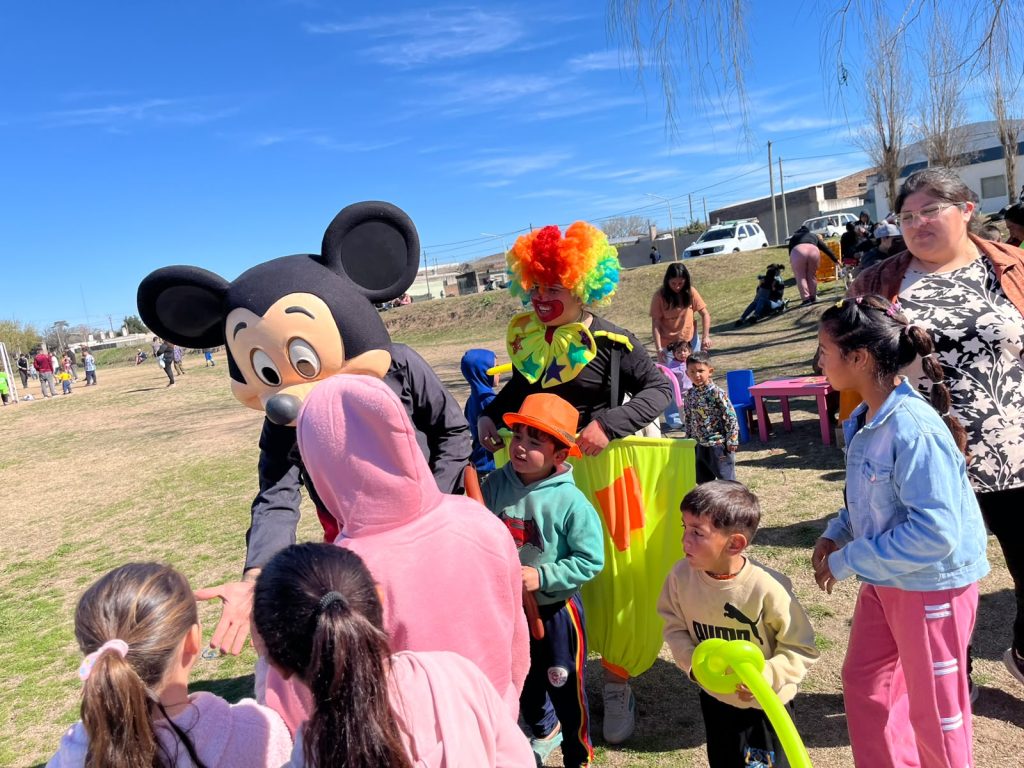 El personaje disfrazado y una payasa reparten globos a un grupo de chicos.