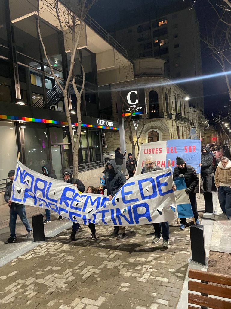 Una columna marcha por la vereda del centro con una bandera pintada a mano.